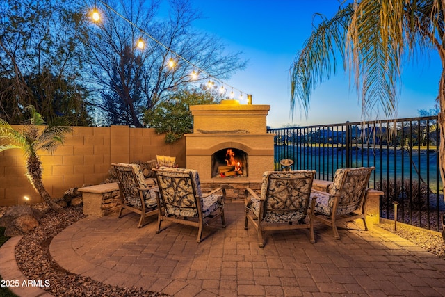 view of patio / terrace with an outdoor living space with a fireplace and fence