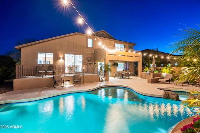 pool at night with a patio area and a fenced in pool