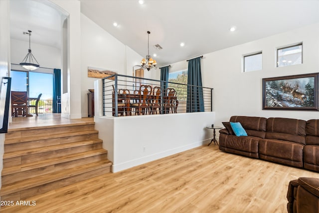 living room with wood finished floors, baseboards, visible vents, high vaulted ceiling, and a chandelier