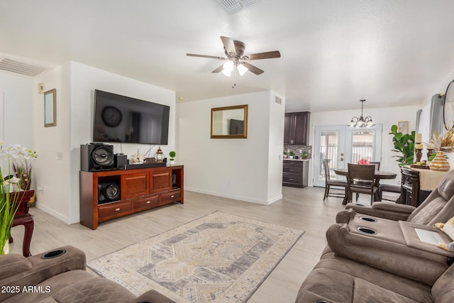 living room with baseboards, visible vents, ceiling fan with notable chandelier, and light wood-style flooring