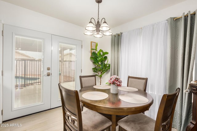 dining room with an inviting chandelier, french doors, and light wood-style flooring