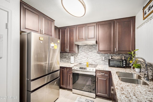 kitchen with stainless steel appliances, decorative backsplash, under cabinet range hood, and a sink