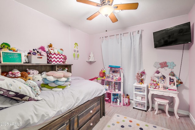 bedroom featuring light wood finished floors, a ceiling fan, and baseboards