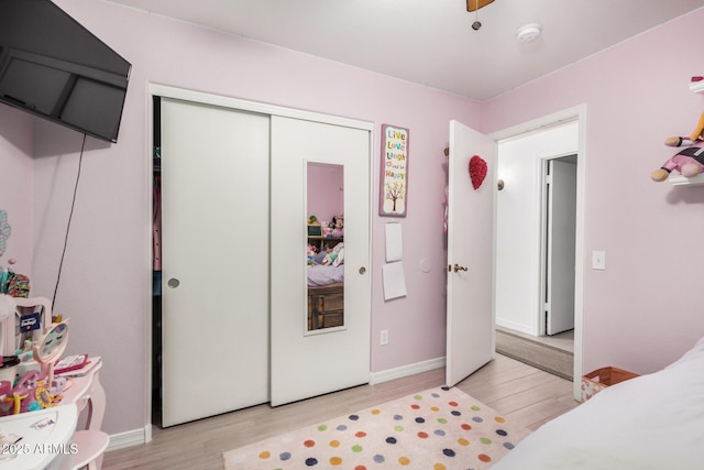 bedroom with light wood-type flooring, a closet, and baseboards