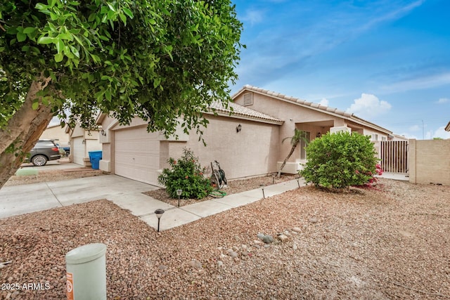 view of front of house with a garage, driveway, a tiled roof, stucco siding, and fence