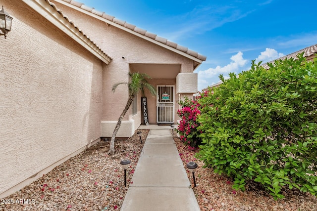 doorway to property with stucco siding and a tiled roof