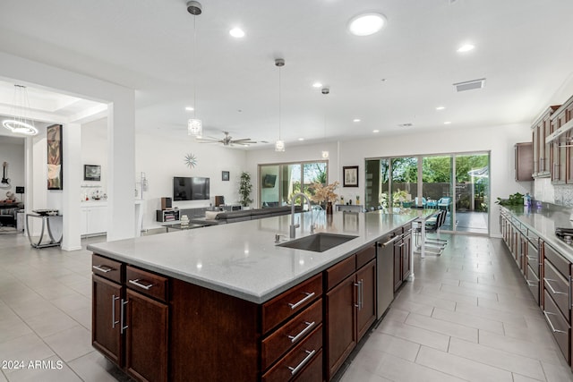 kitchen with pendant lighting, sink, ceiling fan, and a center island with sink