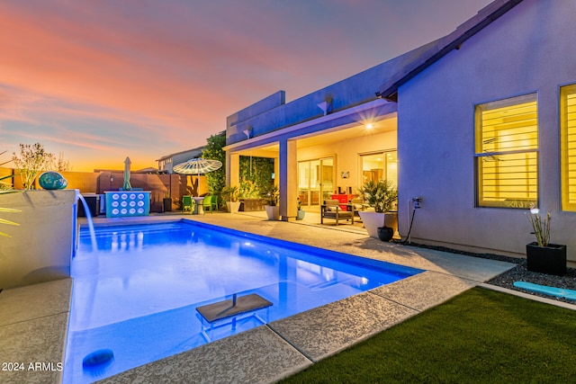 pool at dusk featuring a patio