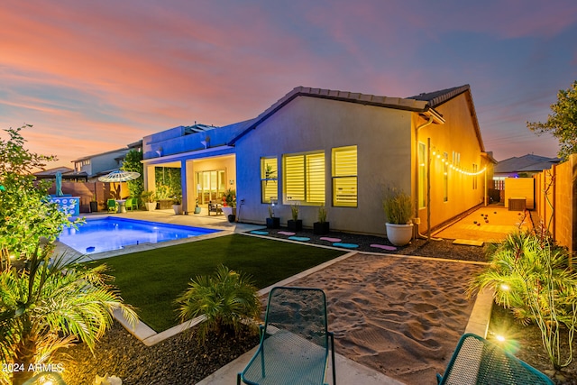 back house at dusk with a yard and a patio