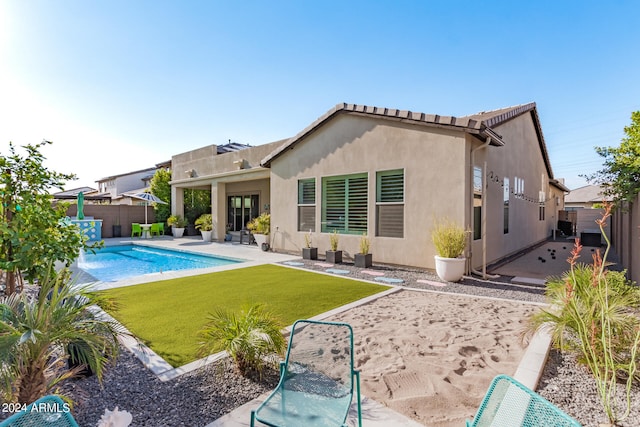 back of property featuring a fenced in pool, a lawn, and a patio