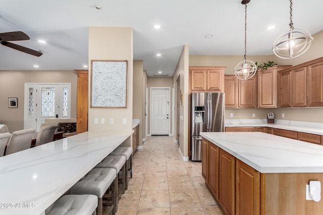 kitchen featuring pendant lighting, light stone counters, stainless steel fridge, and a breakfast bar