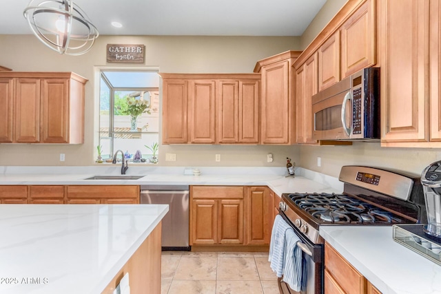 kitchen featuring stainless steel appliances, sink, light tile patterned floors, and decorative light fixtures