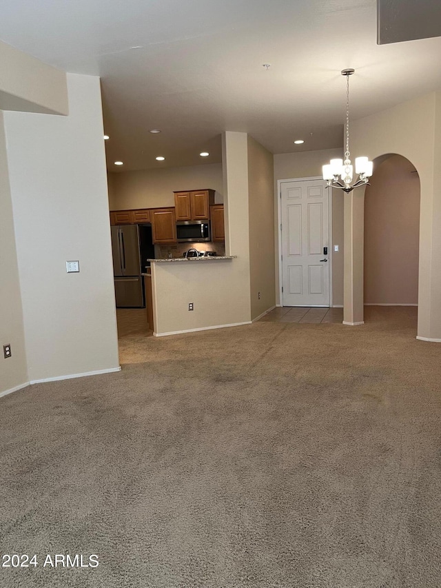 unfurnished living room featuring a notable chandelier and light colored carpet