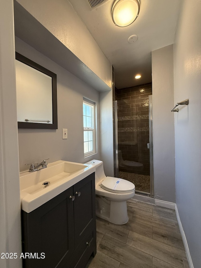 bathroom featuring vanity, toilet, a shower stall, and wood finished floors