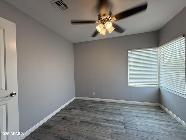 spare room with visible vents, wood finished floors, baseboards, and ceiling fan