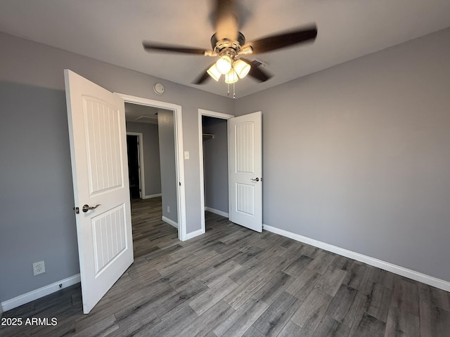 unfurnished bedroom featuring a closet, wood finished floors, baseboards, and ceiling fan