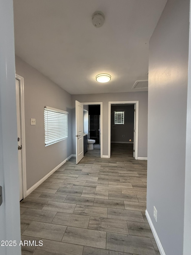 corridor with baseboards and wood finished floors