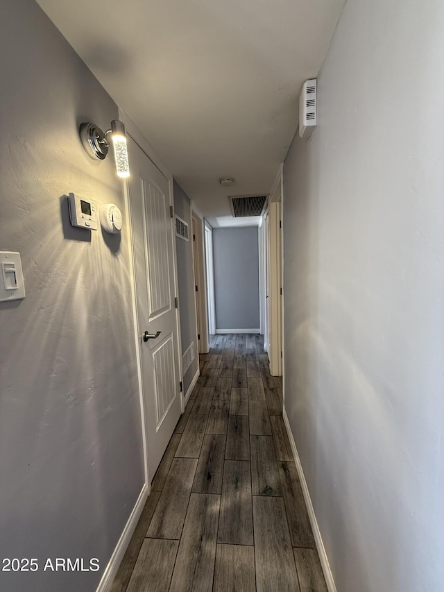 hall featuring dark wood-type flooring, baseboards, and visible vents