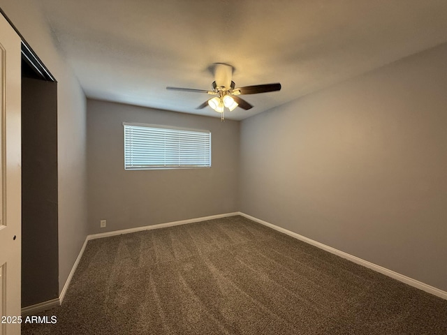 empty room featuring ceiling fan, baseboards, and dark carpet
