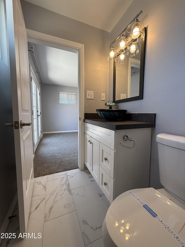bathroom with toilet, marble finish floor, baseboards, and vanity