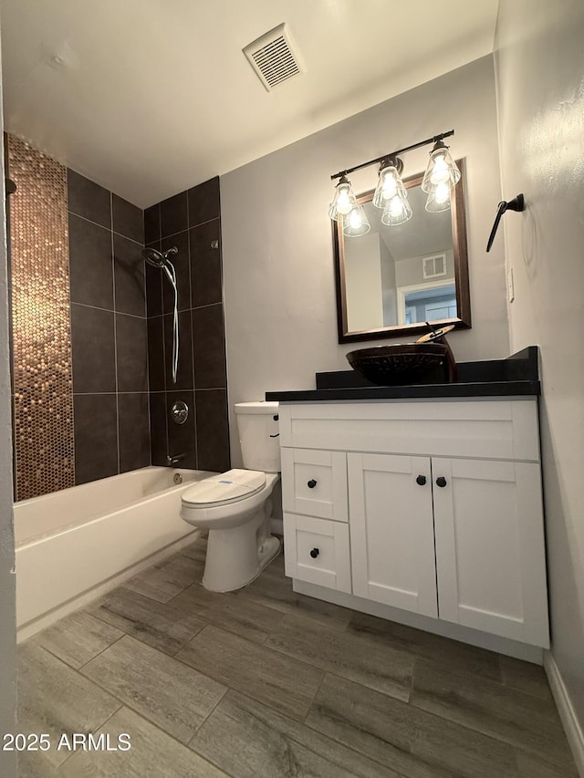 bathroom with toilet, visible vents,  shower combination, and vanity