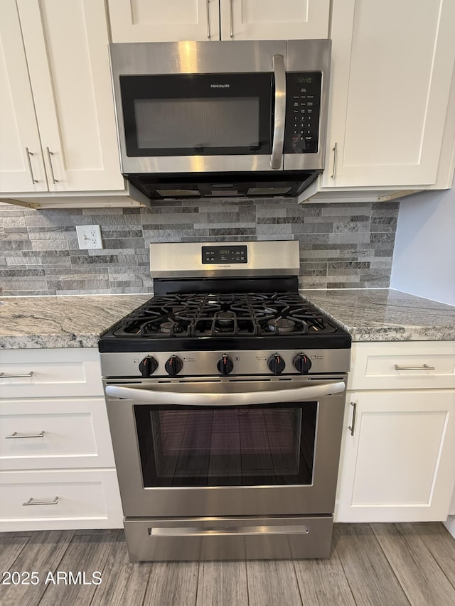 kitchen featuring white cabinetry, stainless steel appliances, and wood finished floors