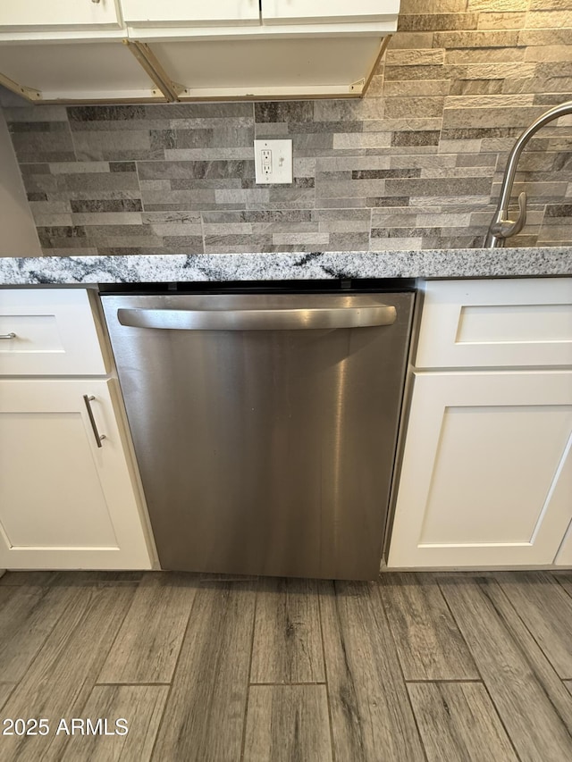 room details with wood finished floors, decorative backsplash, white cabinets, and dishwasher