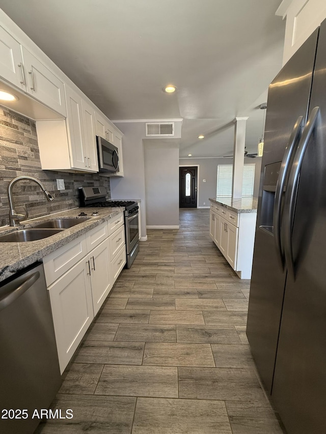 kitchen featuring a sink, stainless steel appliances, tasteful backsplash, visible vents, and white cabinetry