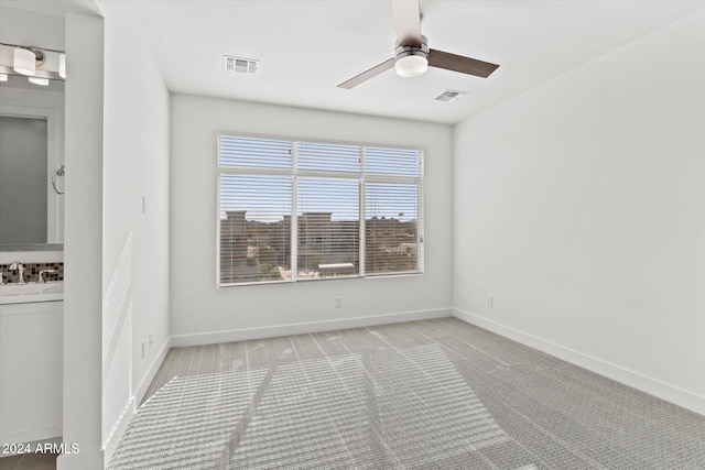 carpeted empty room featuring ceiling fan and sink