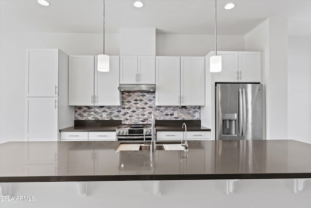 kitchen featuring a kitchen bar, white cabinetry, pendant lighting, and stainless steel appliances