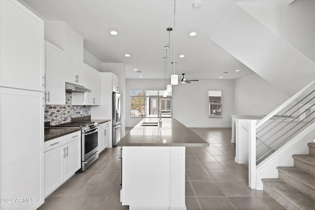 kitchen with a kitchen island with sink, sink, ceiling fan, appliances with stainless steel finishes, and decorative light fixtures