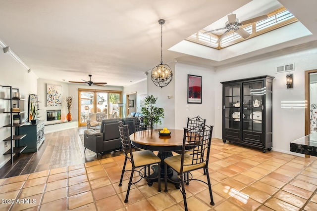 dining area with ornamental molding, ceiling fan with notable chandelier, and a skylight