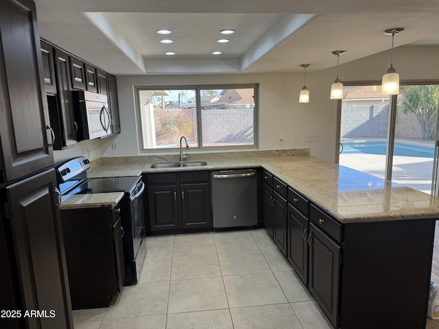 kitchen featuring sink, hanging light fixtures, appliances with stainless steel finishes, a tray ceiling, and kitchen peninsula