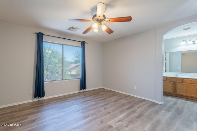 931 S Racine Ln, Gilbert, AZ 85296 - unfurnished bedroom featuring arched walkways, light wood finished floors, connected bathroom, and ceiling fan