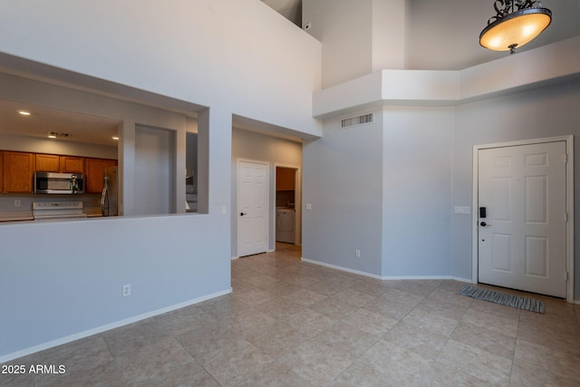 931 S Racine Ln, Gilbert, AZ 85296 - unfurnished living room featuring a towering ceiling, light tile patterned floors, and washer / clothes dryer