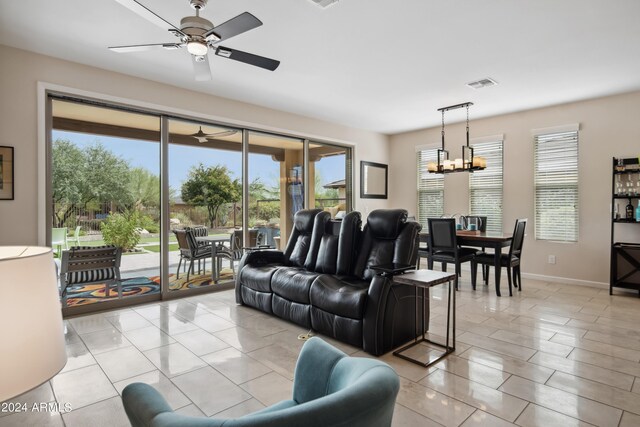 living room with light tile patterned flooring, ceiling fan with notable chandelier, and plenty of natural light