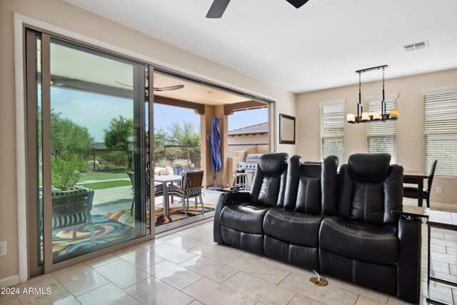 living room featuring ceiling fan with notable chandelier and light tile patterned floors