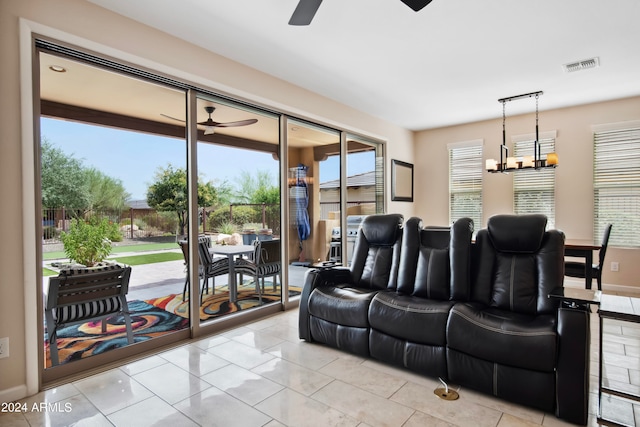 tiled living room with ceiling fan with notable chandelier