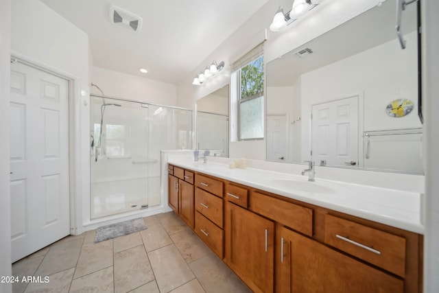 bathroom with dual vanity, an enclosed shower, and tile patterned floors