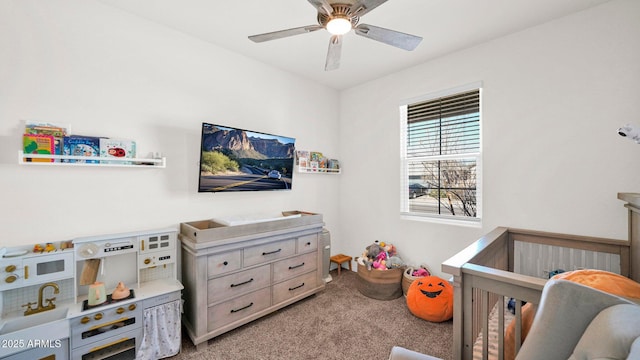 bedroom with a crib, ceiling fan, and light colored carpet