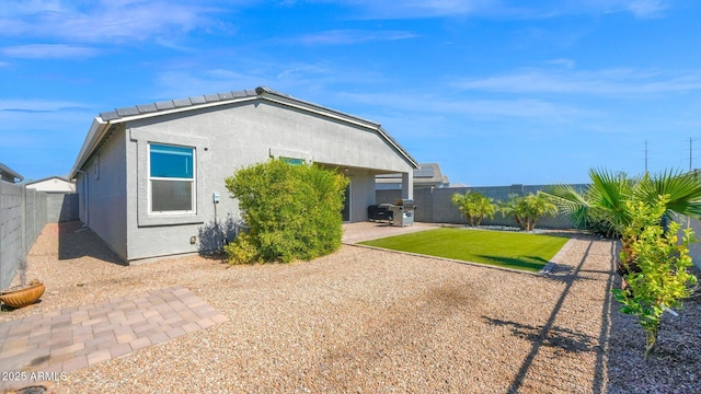 rear view of house with a patio area, a fenced backyard, and stucco siding