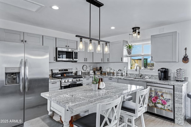 kitchen with light stone countertops, sink, pendant lighting, a breakfast bar, and appliances with stainless steel finishes