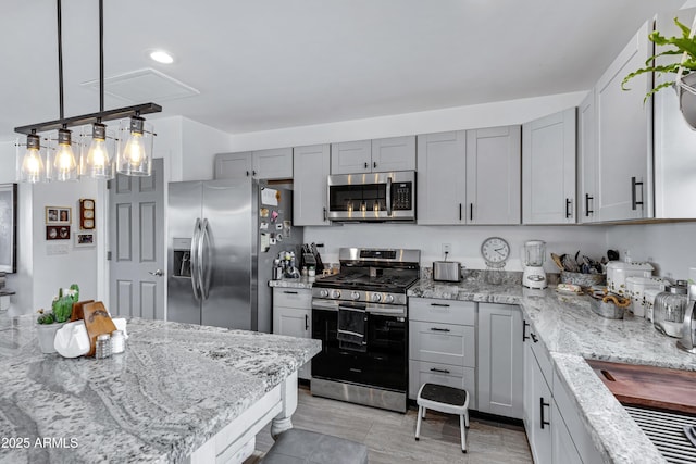 kitchen with gray cabinets, light stone counters, pendant lighting, and stainless steel appliances