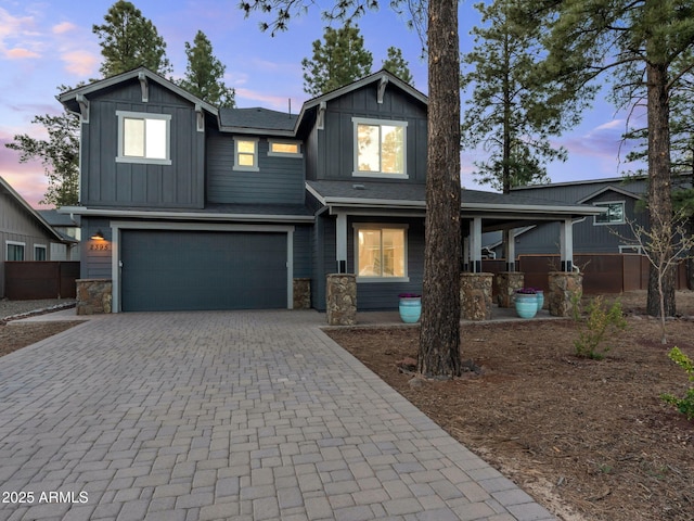 2395 S Polaris Way, Flagstaff, AZ 86001 - view of front of home featuring board and batten siding, a garage, decorative driveway, stone siding, and covered porch