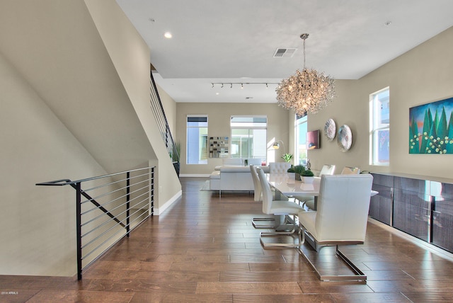 dining room with a chandelier, a healthy amount of sunlight, dark hardwood / wood-style floors, and track lighting