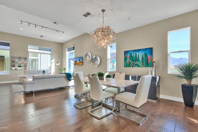 dining area featuring track lighting, a notable chandelier, and dark hardwood / wood-style floors