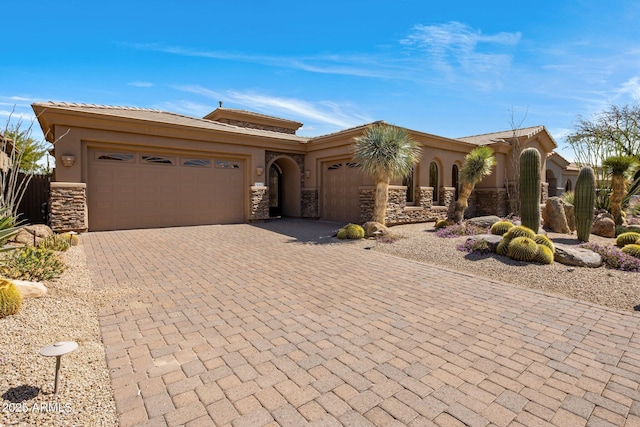 view of front facade with decorative driveway, stone siding, an attached garage, and stucco siding