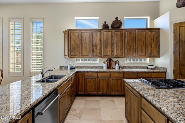 kitchen featuring a sink, light stone counters, brown cabinetry, and stainless steel appliances