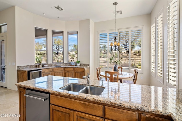 kitchen with brown cabinetry, visible vents, light stone countertops, and a sink