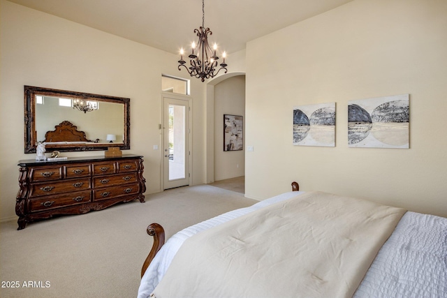 bedroom with light colored carpet, arched walkways, a notable chandelier, and access to outside